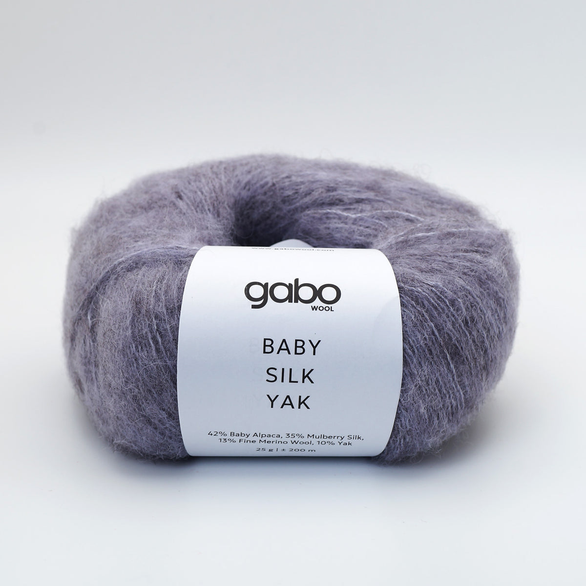 A skein of Gabo Wool Baby Silk Yak yarn in a soft lavender-gray color, featuring a white paper label with black text, set against a clean white background.